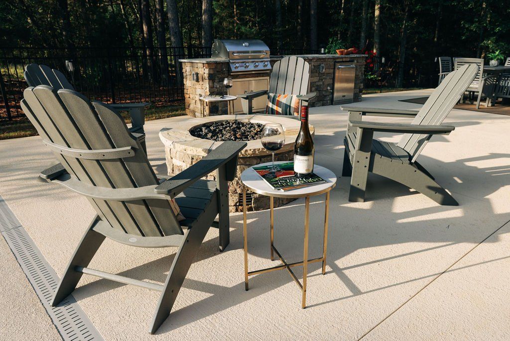 Patio with two gray chairs, small table, and fire pit on a sunny deck.
