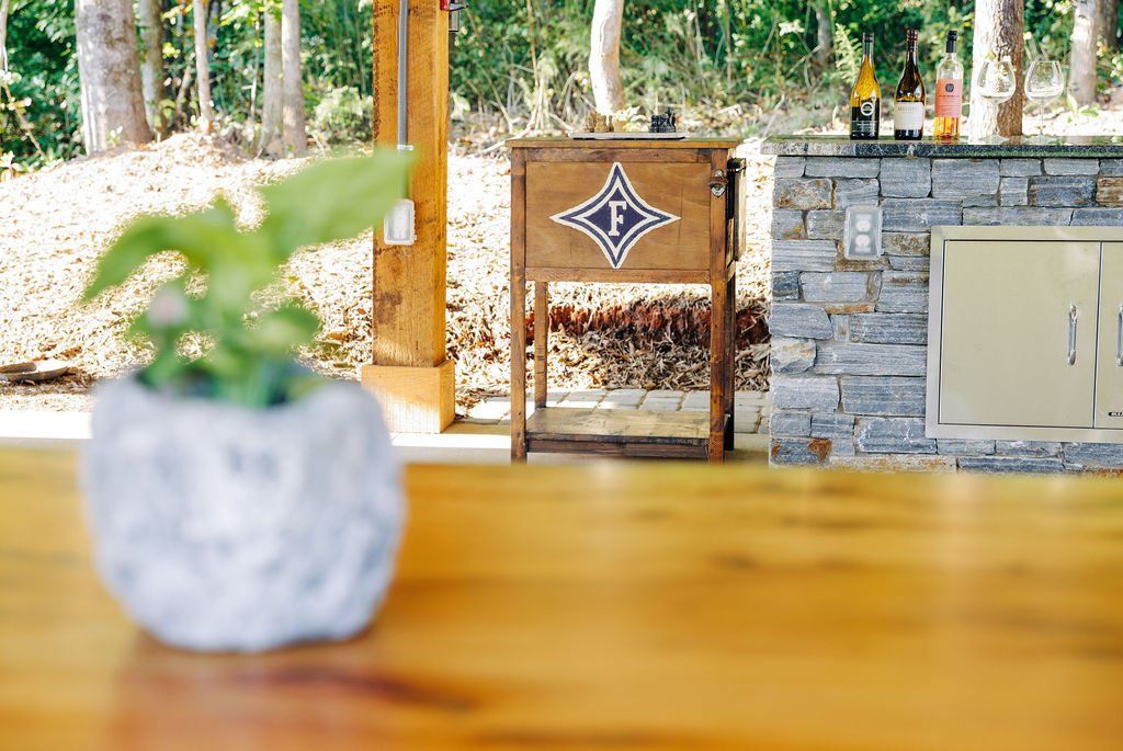 Blurred potted plant on wooden table with outdoor stone wall and wooden gate in the background