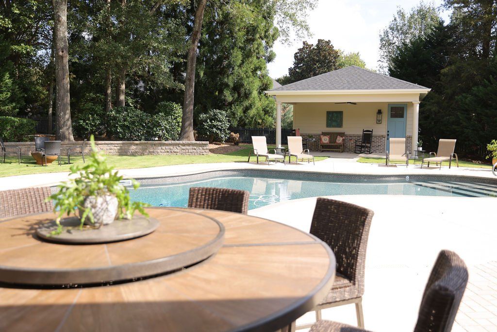 Backyard patio with pool, lounge chairs, and a small gazebo in the background