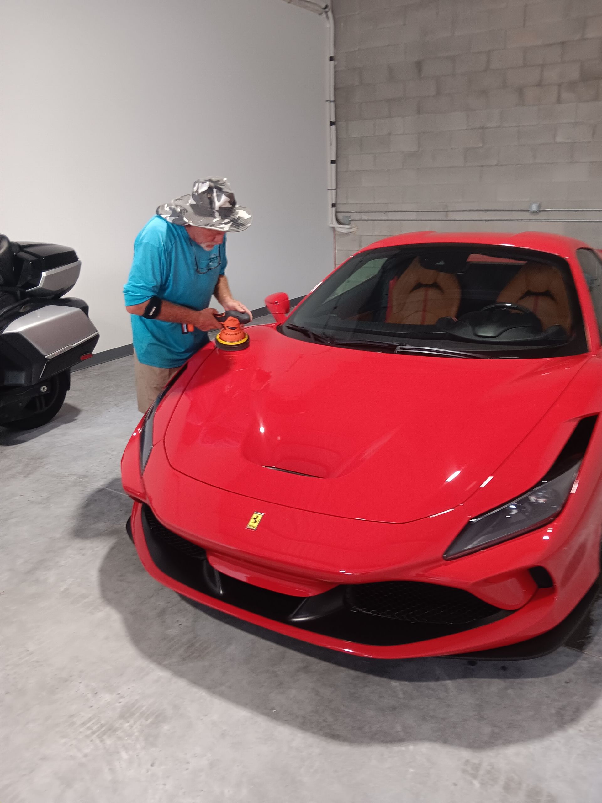 Person pressure-washing a white car with thick foam in a garage
