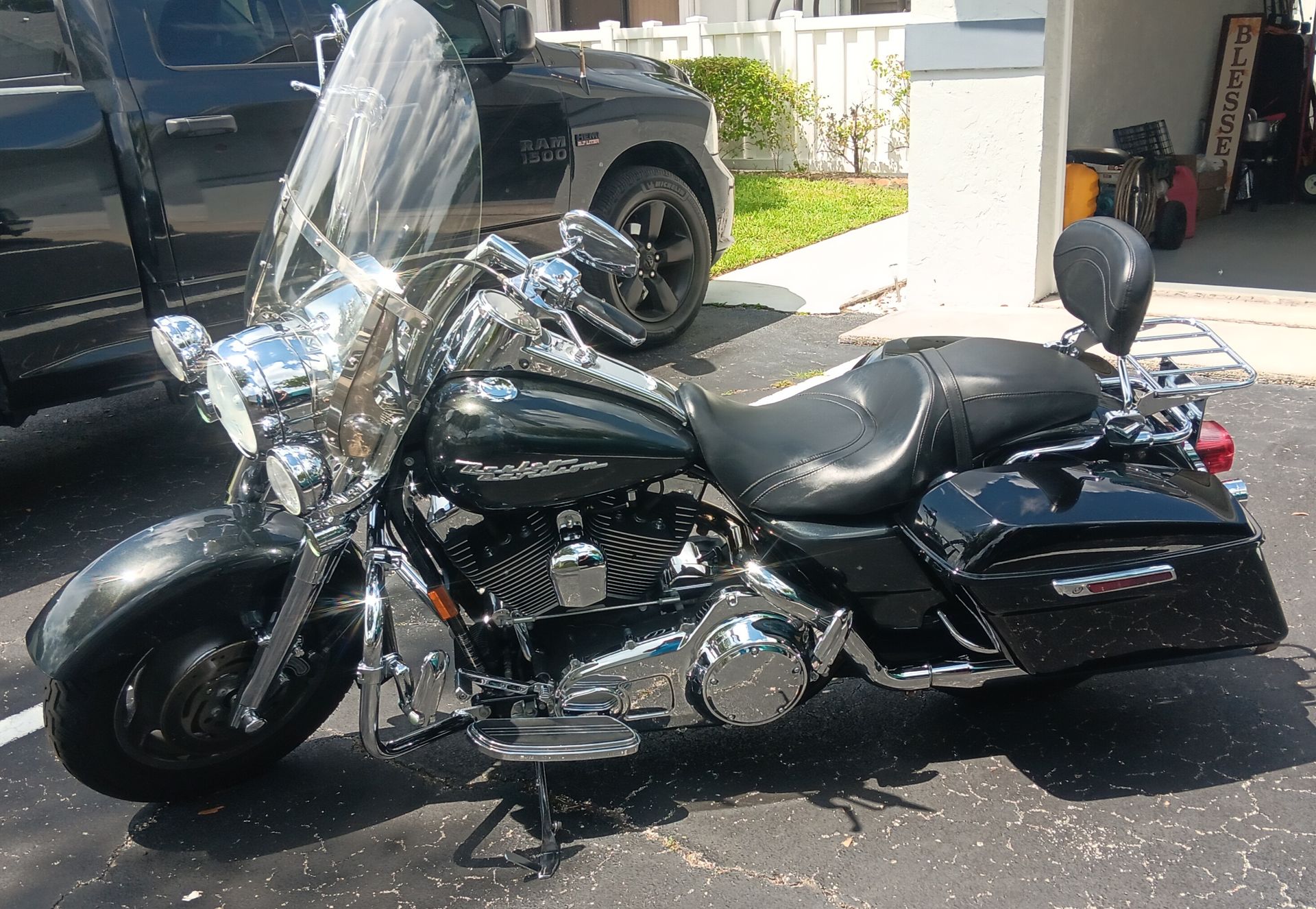 Black touring motorcycle parked in a driveway, with chrome details and a tall windshield