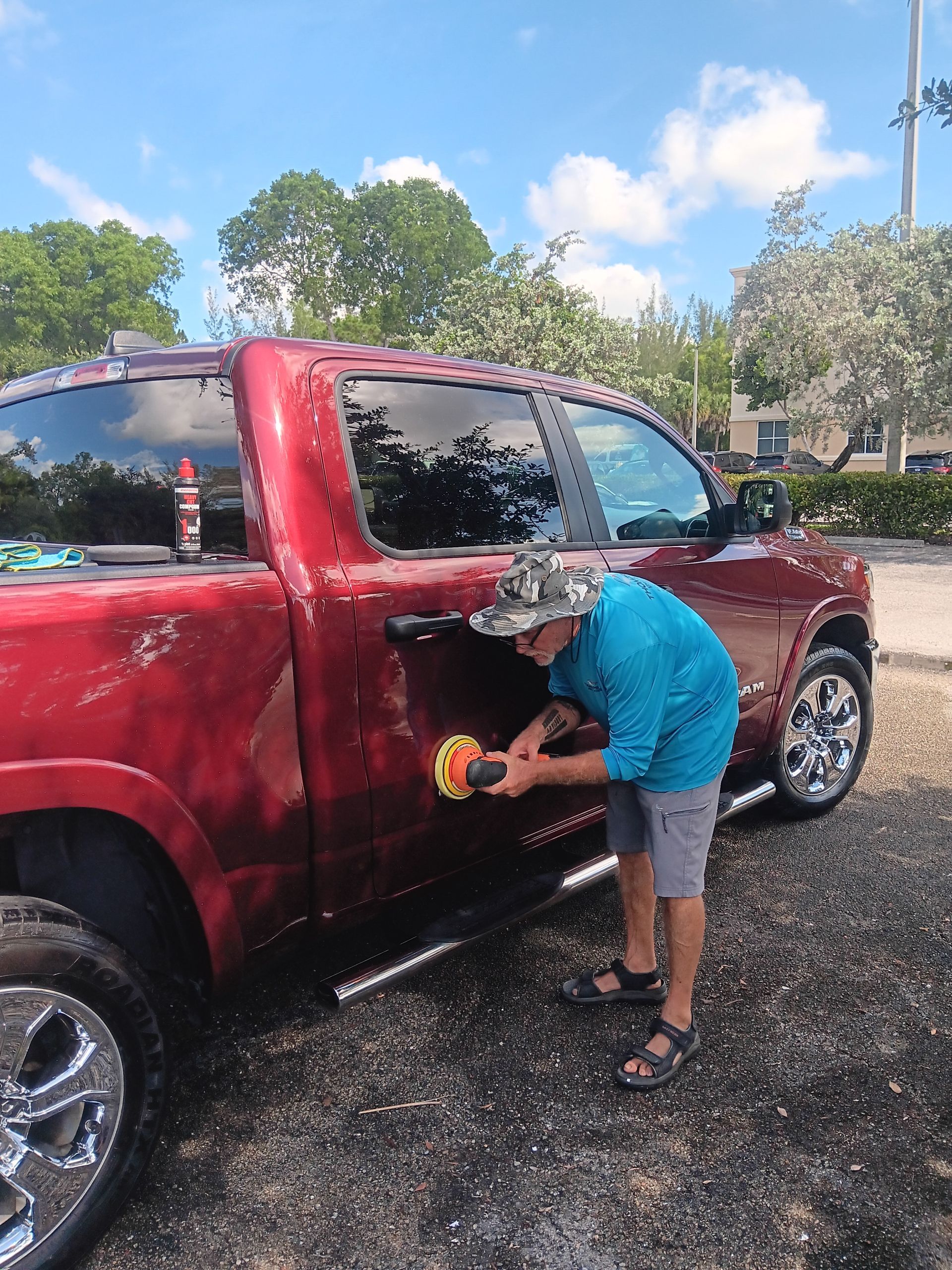 Person cleaning a car’s center console and gear shift with a blue cloth and orange glove