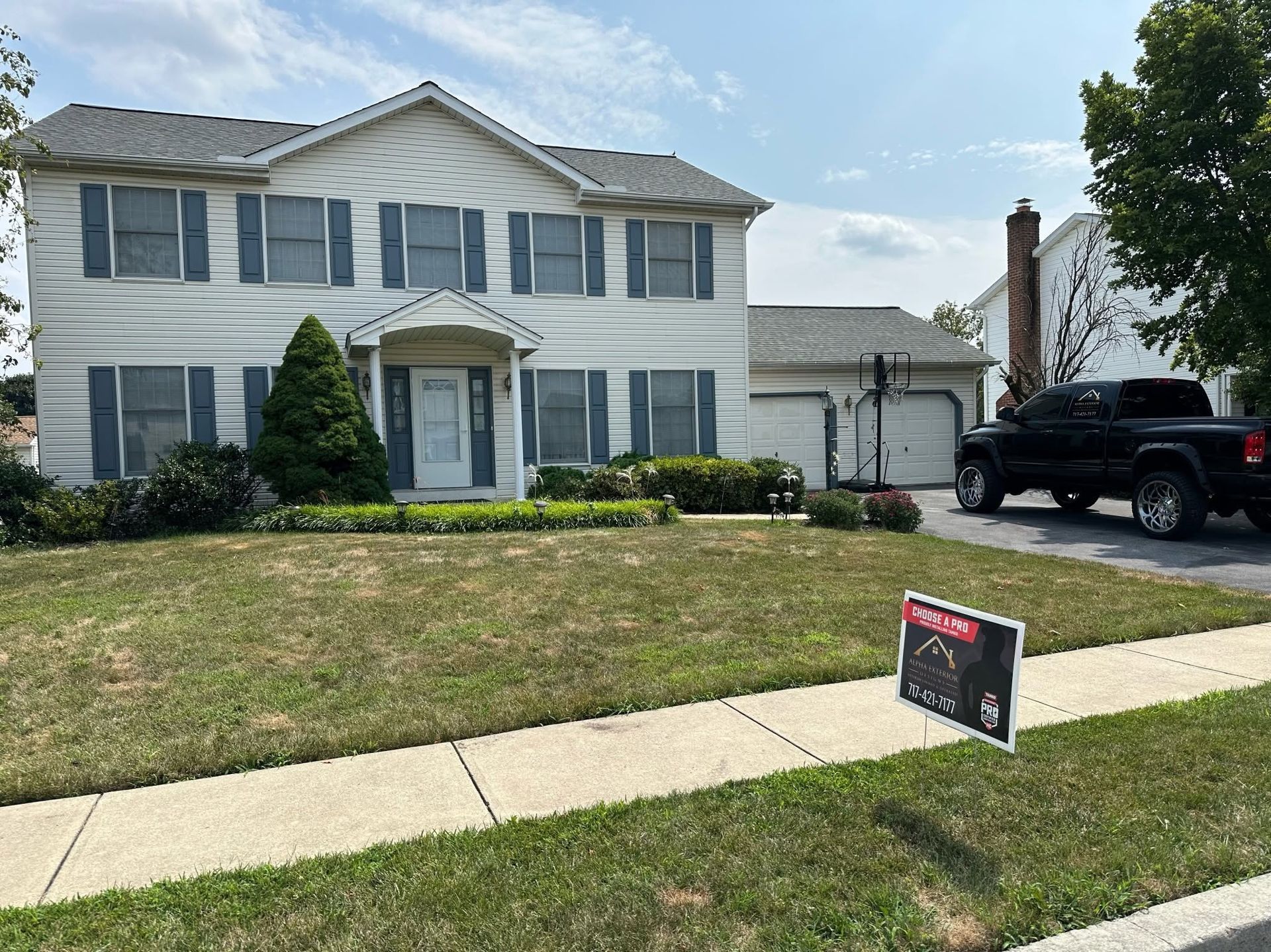 Two-story white house with blue shutters and a For Sale sign in the front yard