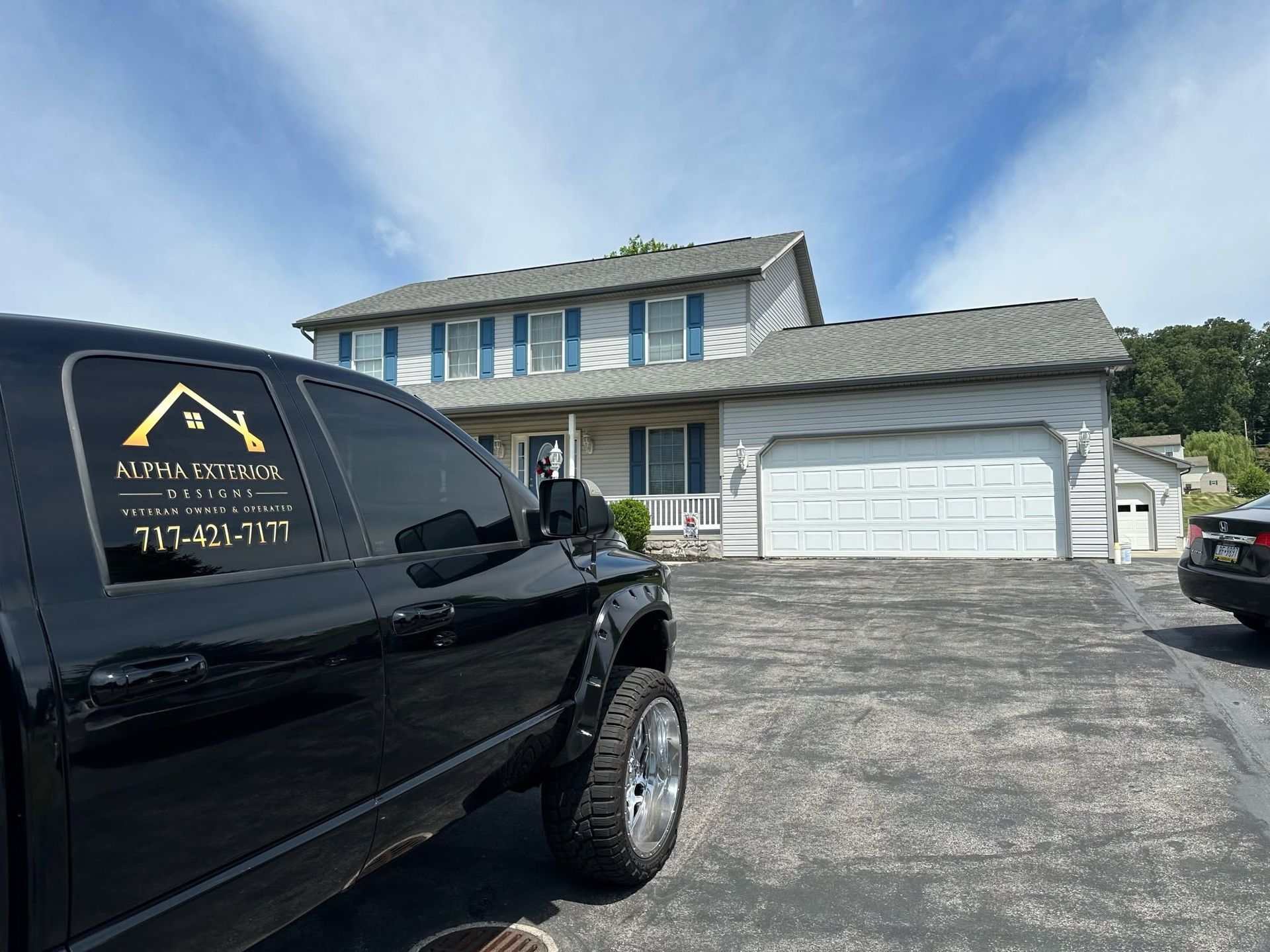 Black service van parked in front of a two-story house with a large white garage door.