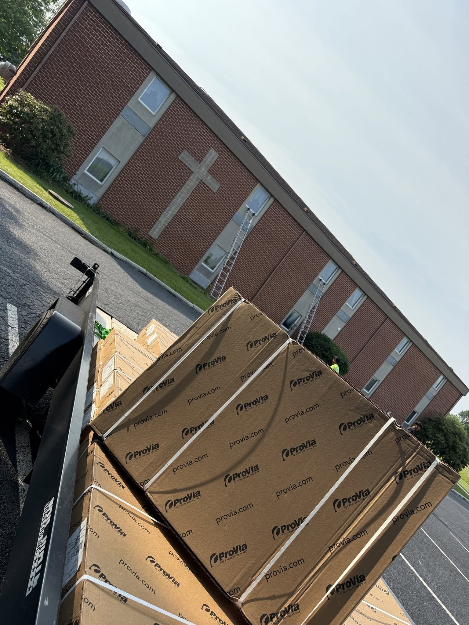 Stacked cardboard boxes beside a brick building in a parking lot, shot at a tilted angle.