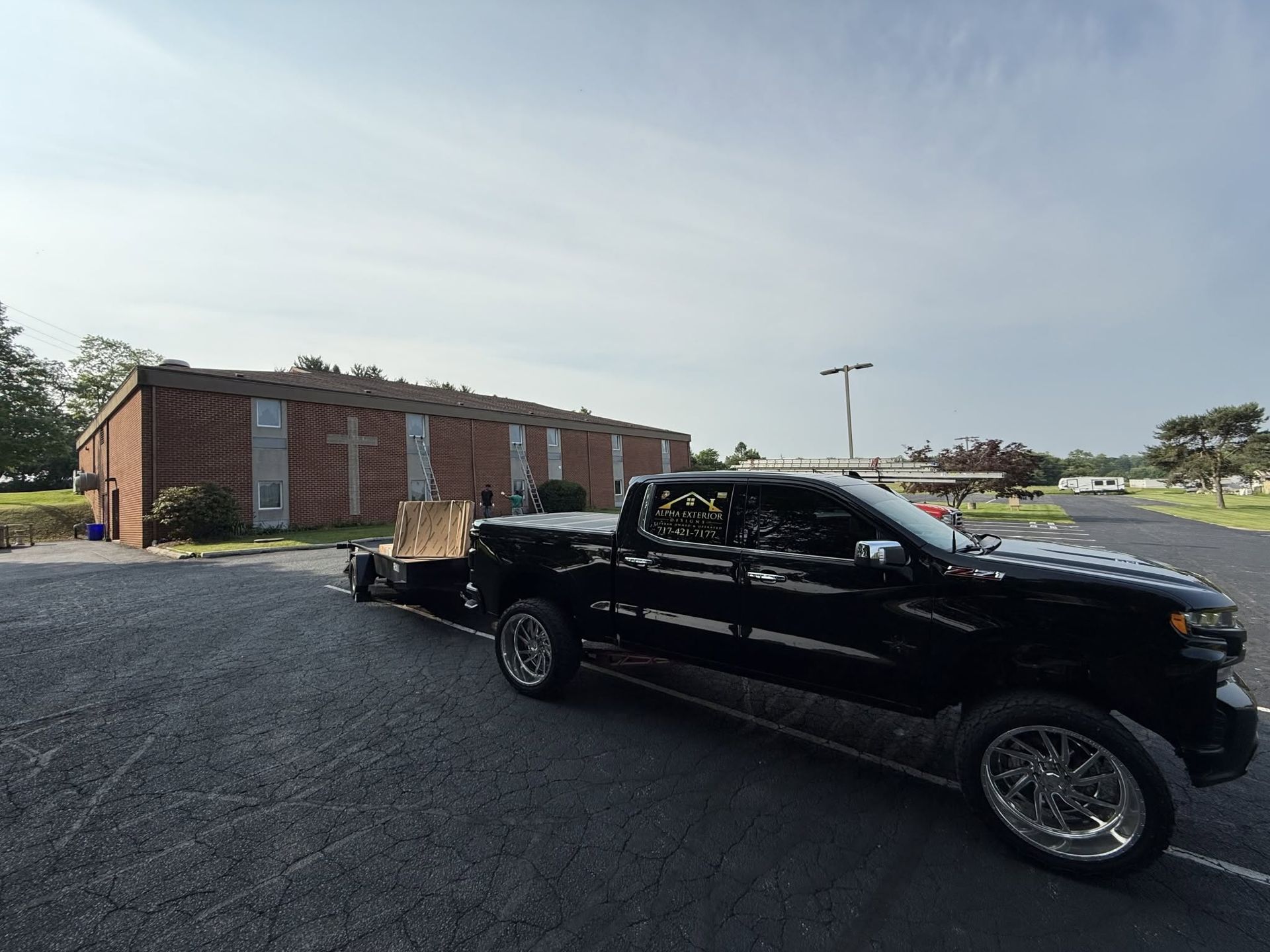Black pickup truck parked beside a brick building on a sunny day