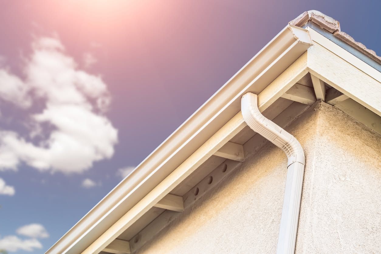 House roof and gutter against a pink sky with clouds