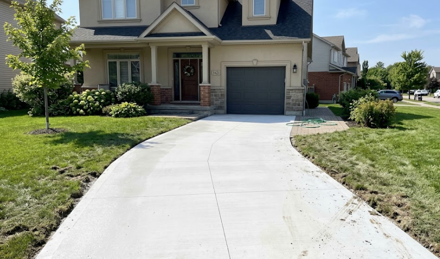 Freshly poured smooth concrete driveway installed by a contractor in front of a suburban home.