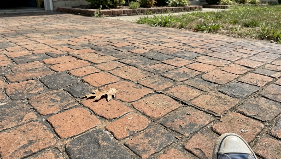 Close up of decorative stamped concrete driveway featuring a brown cobblestone pattern.