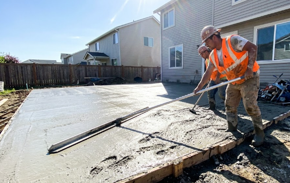 Professional concrete contractors smoothing wet concrete on a job site.