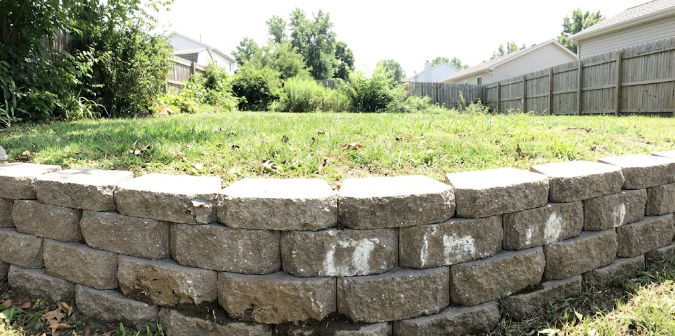 A beautiful concrete block retaining wall holding back a green lawn in a Harrisonburg backyard.