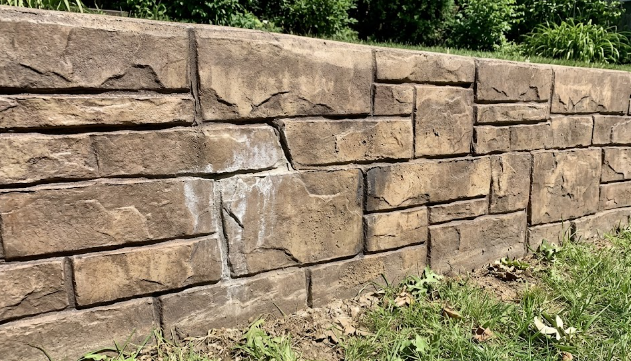 Close up view of a decorative stamped concrete retaining wall designed to look like natural stone.