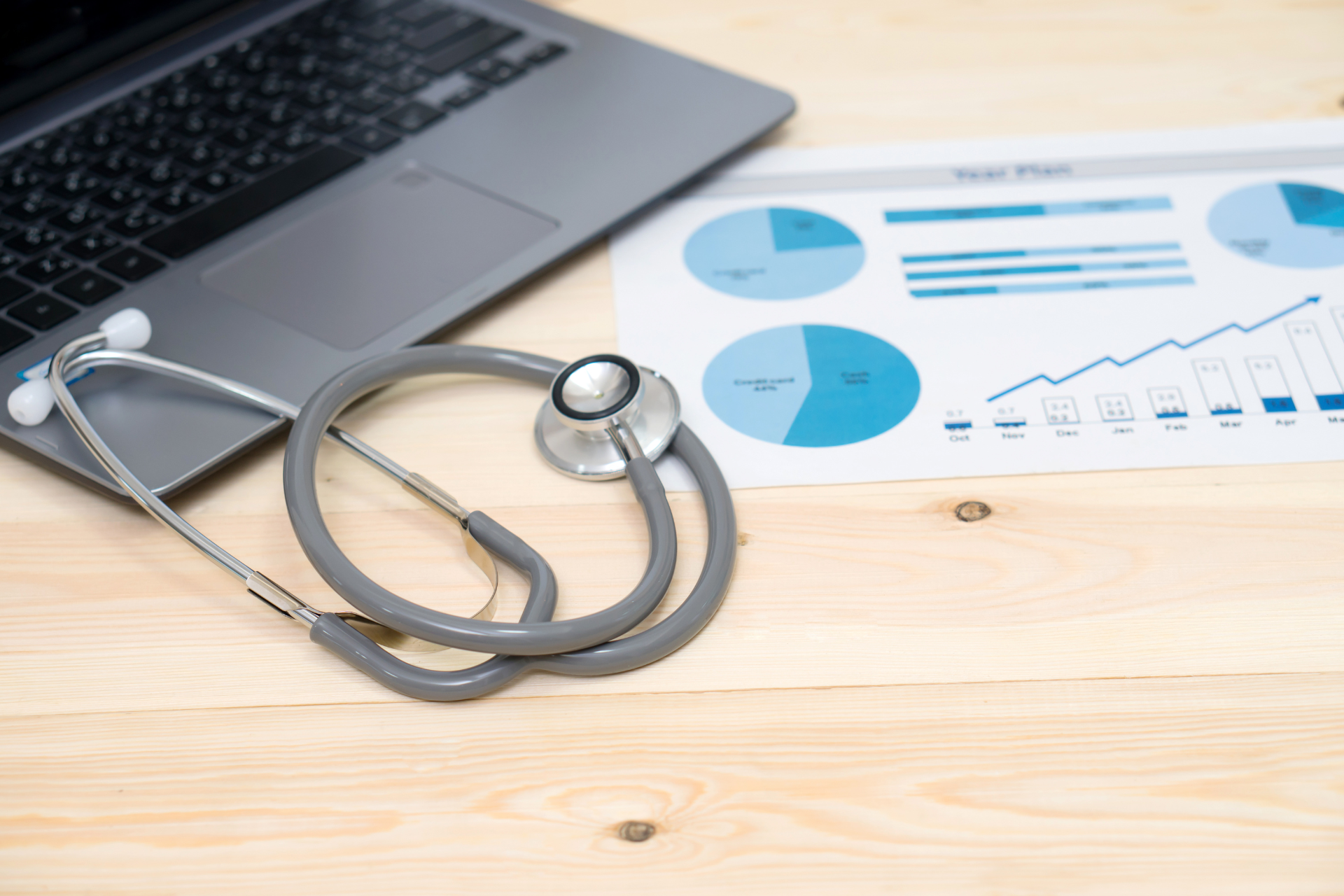 Stethoscope, laptop, and medical business report on wooden desk