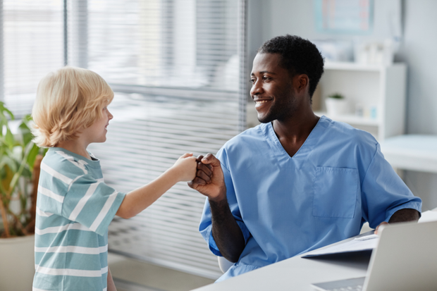 A young boy is shaking hands with a doctor in a hospital.