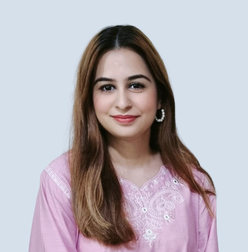 A woman wearing a pink shirt and earrings is smiling for the camera.