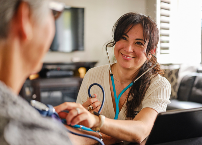 A medical provider is smiling while taking a patient's blood pressure