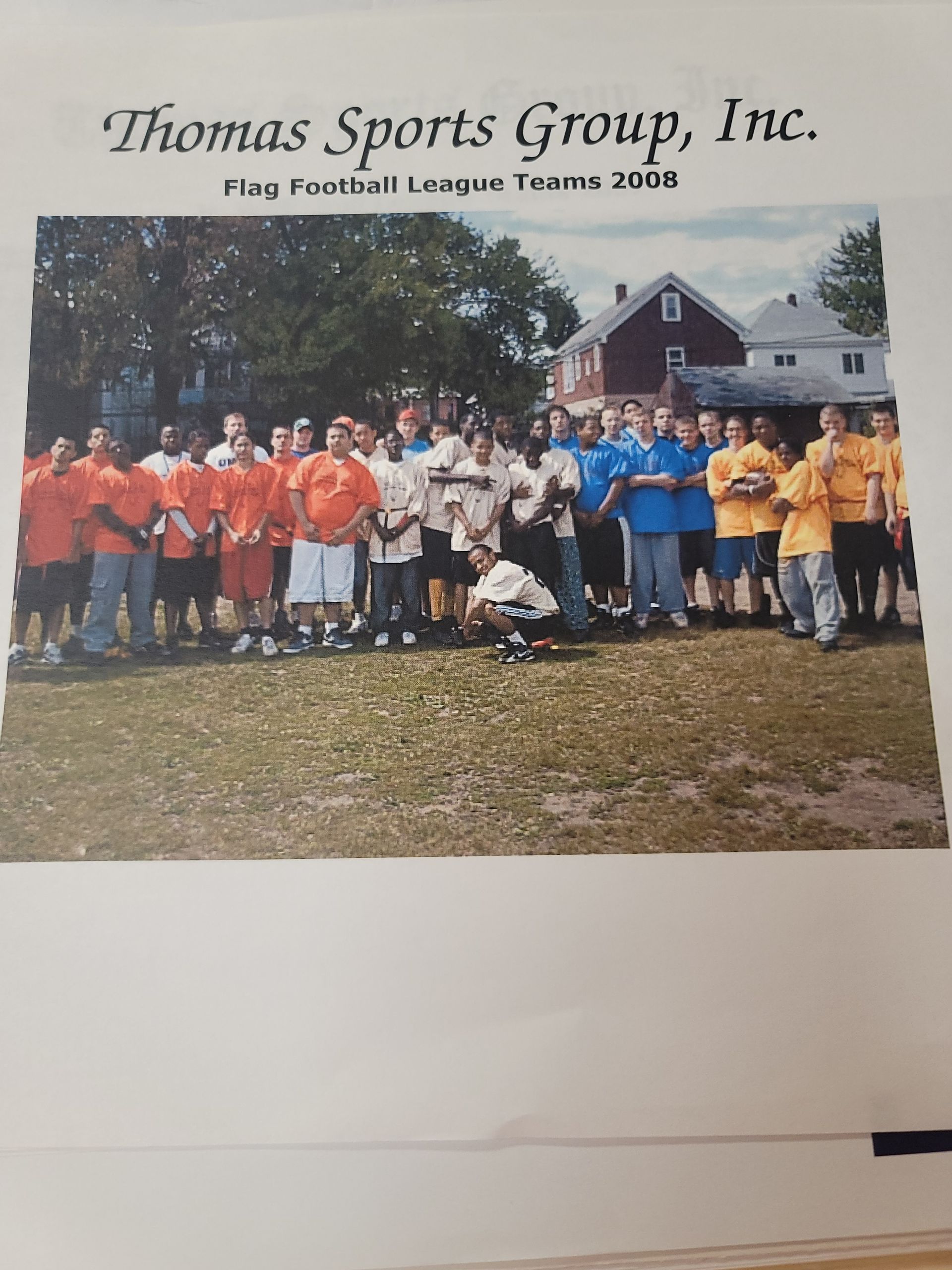 Thomas Sports Group, Inc. youth softball team posing outdoors in orange, white, and blue uniforms