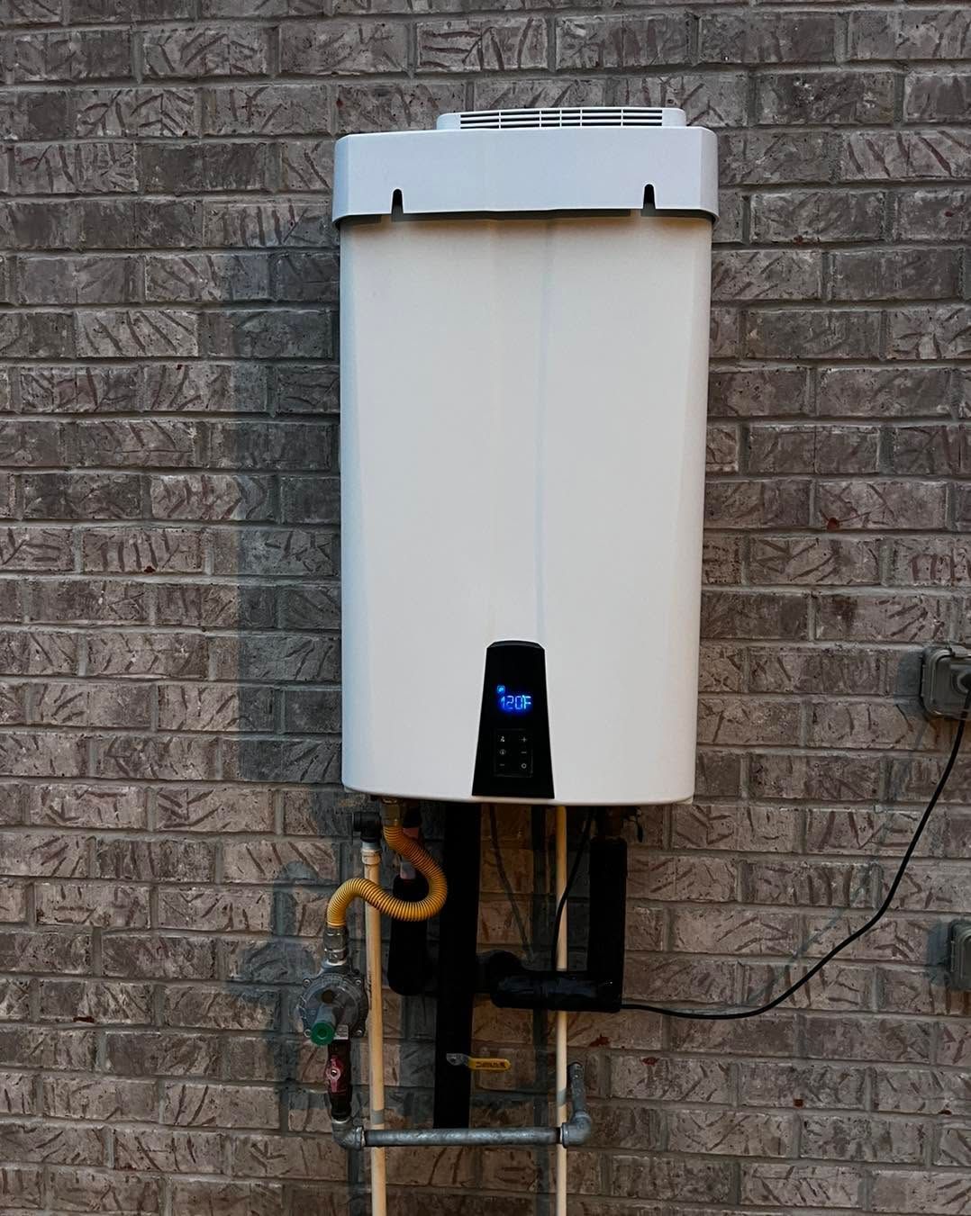 White outdoor tankless water heater mounted on a brick wall with pipes and a small display panel