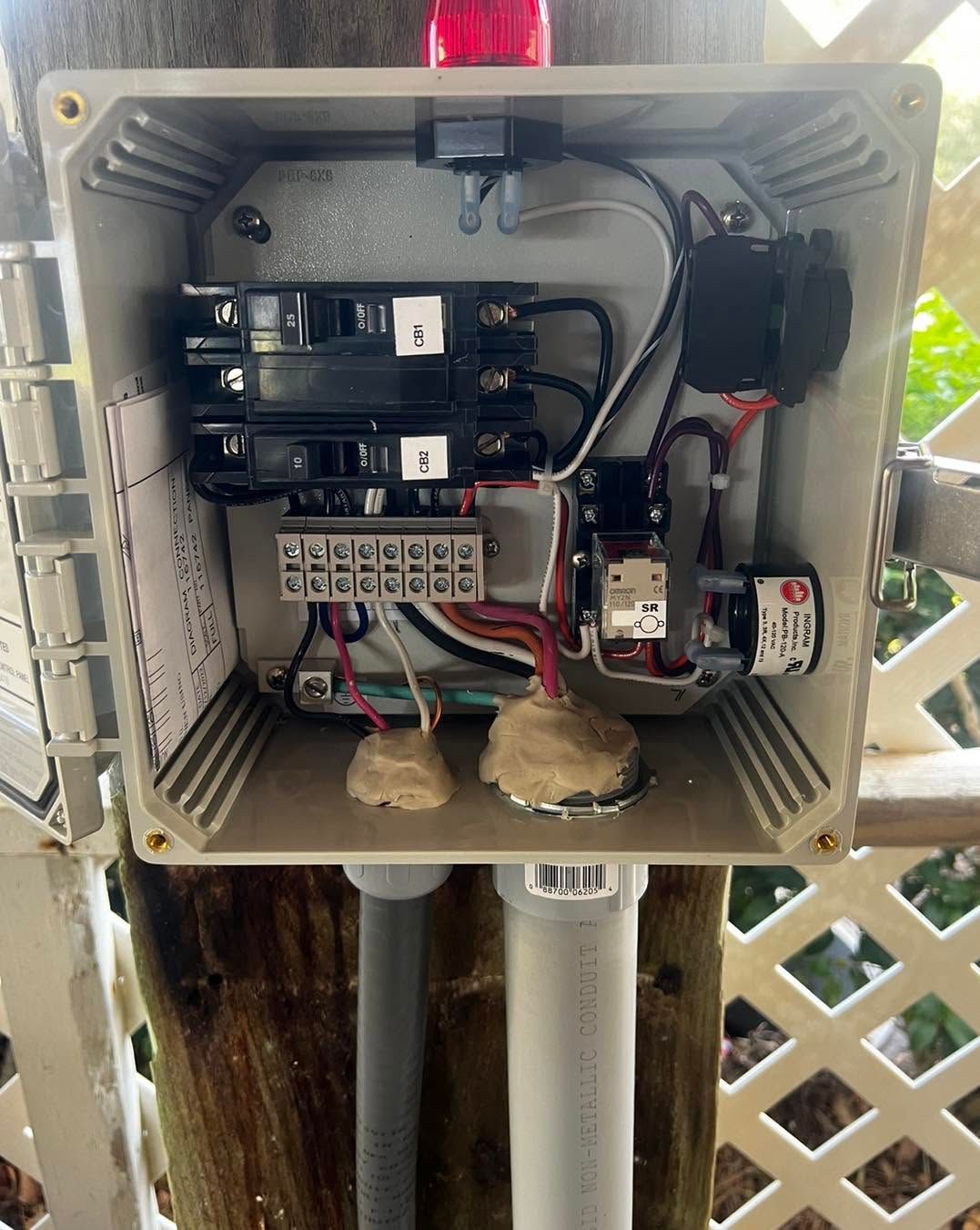 Open electrical control box with relays, wiring, and circuit components mounted inside.