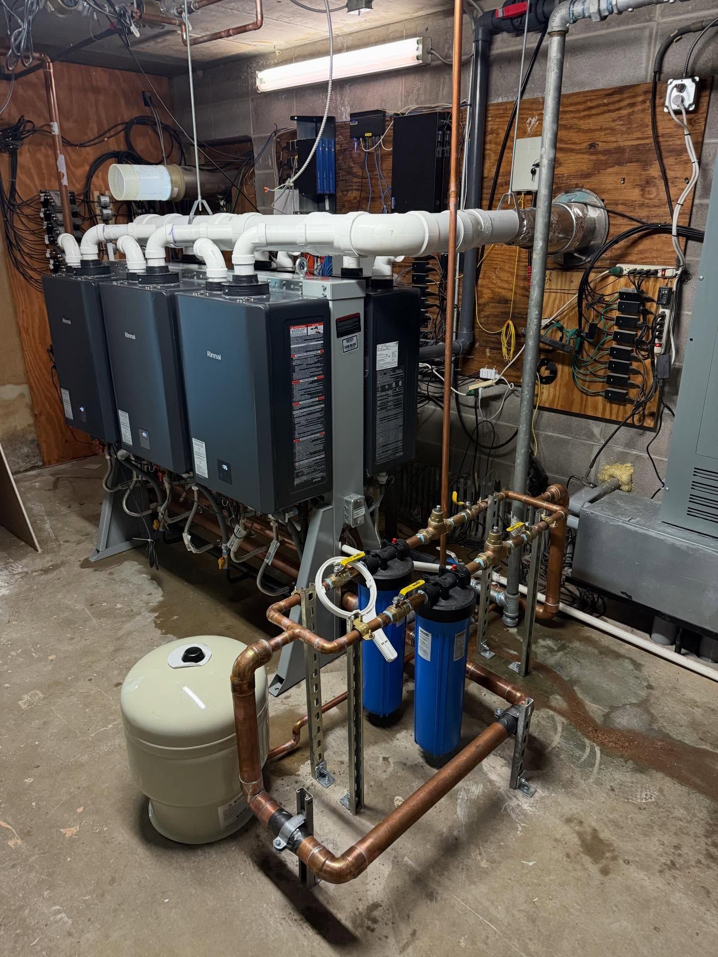 Basement mechanical room with HVAC units, copper piping, and a beige expansion tank