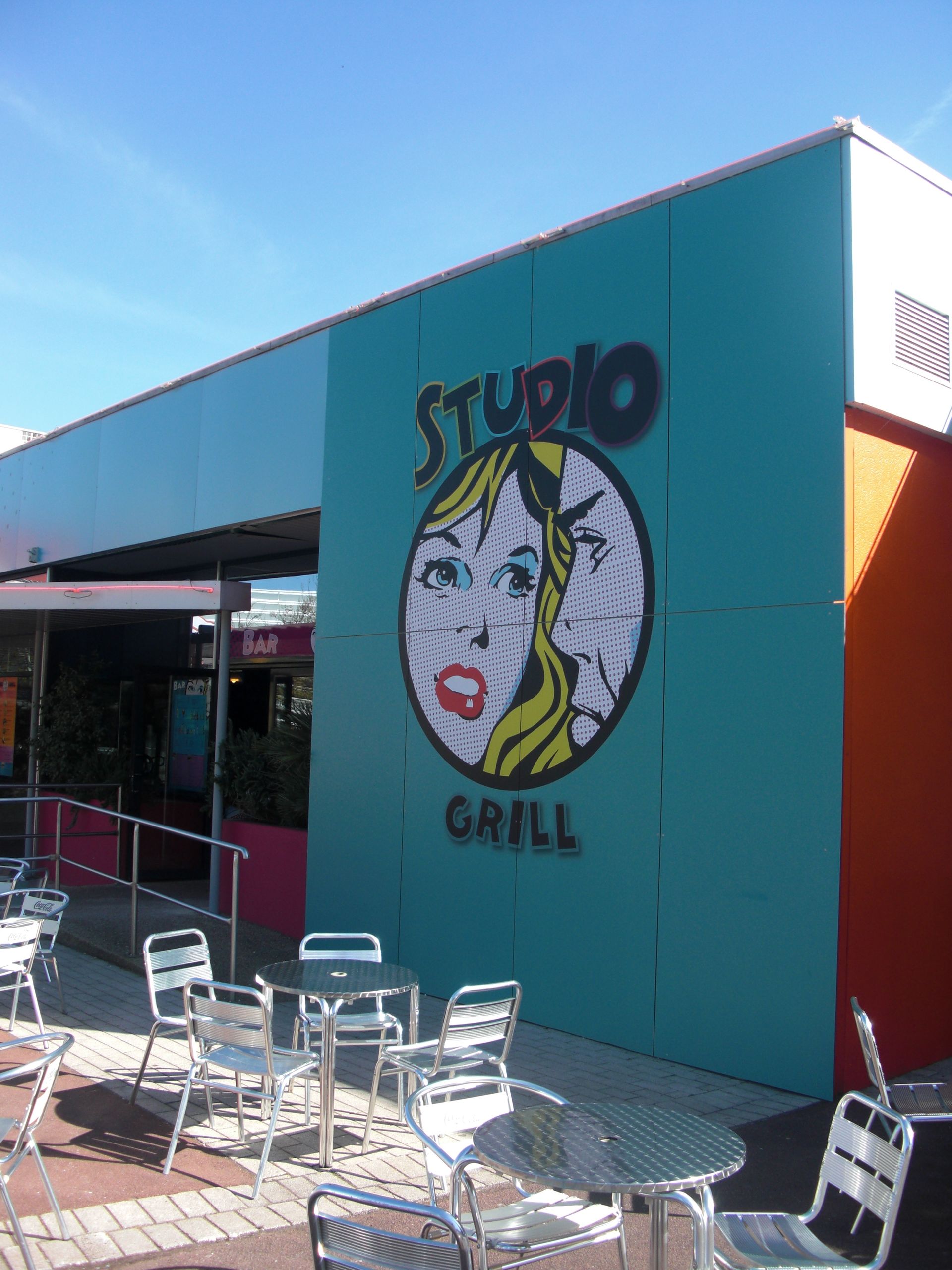 Die Außenseite eines Studio-Grill-Restaurants mit Tischen und Stühlen