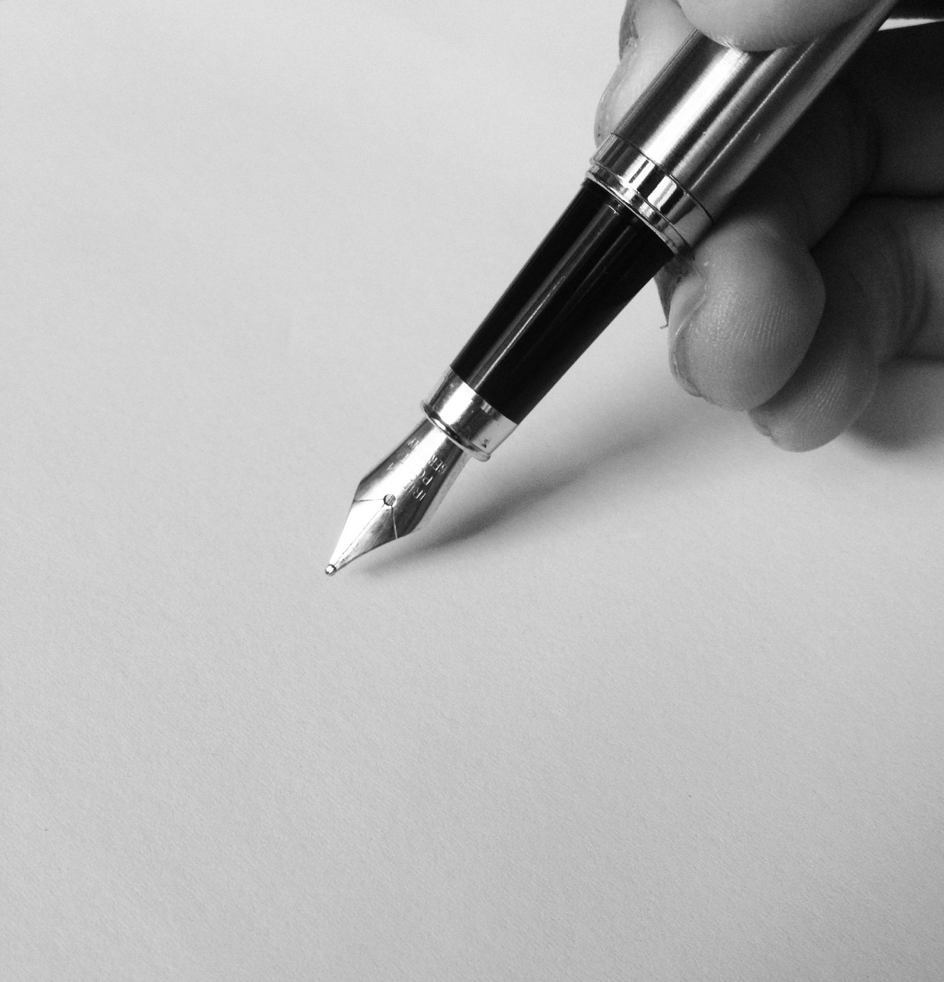 A person is writing with a fountain pen on a piece of paper