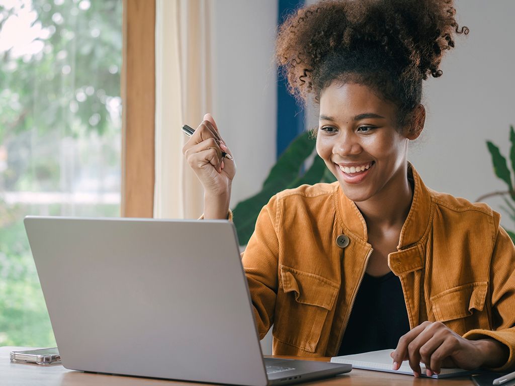 A woman is sitting at a table using a laptop computer.