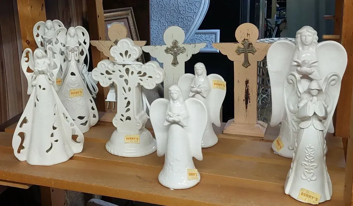 Shelf of white ceramic angels and crosses.
