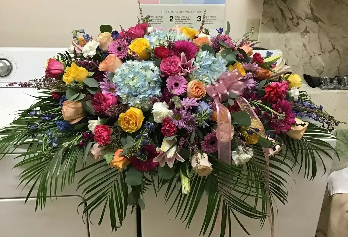 Colorful floral arrangement with pink, blue, yellow, and red flowers and green foliage.