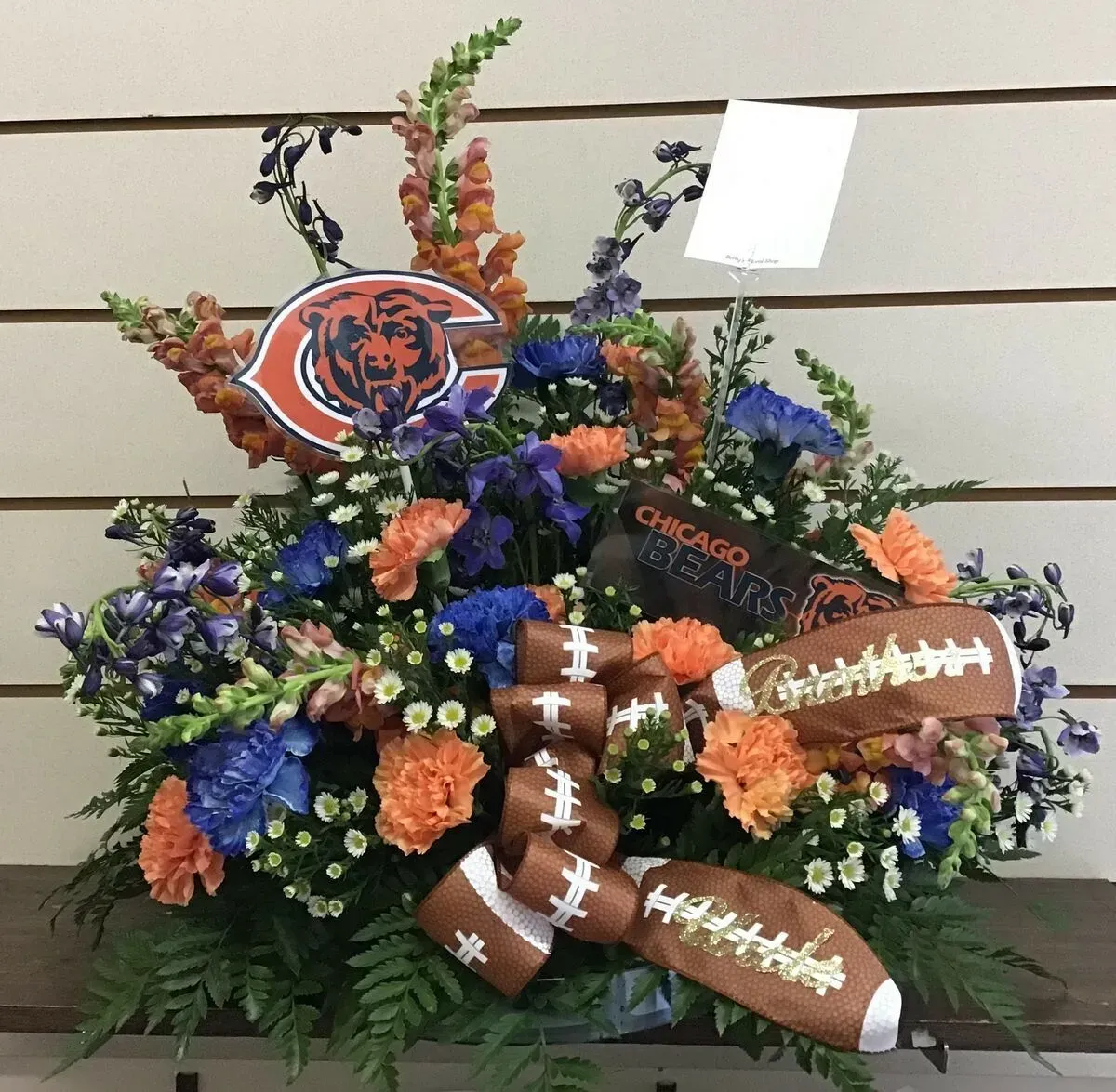 Flower arrangement with Chicago Bears logo, football accents, and blue, orange, and green flowers.