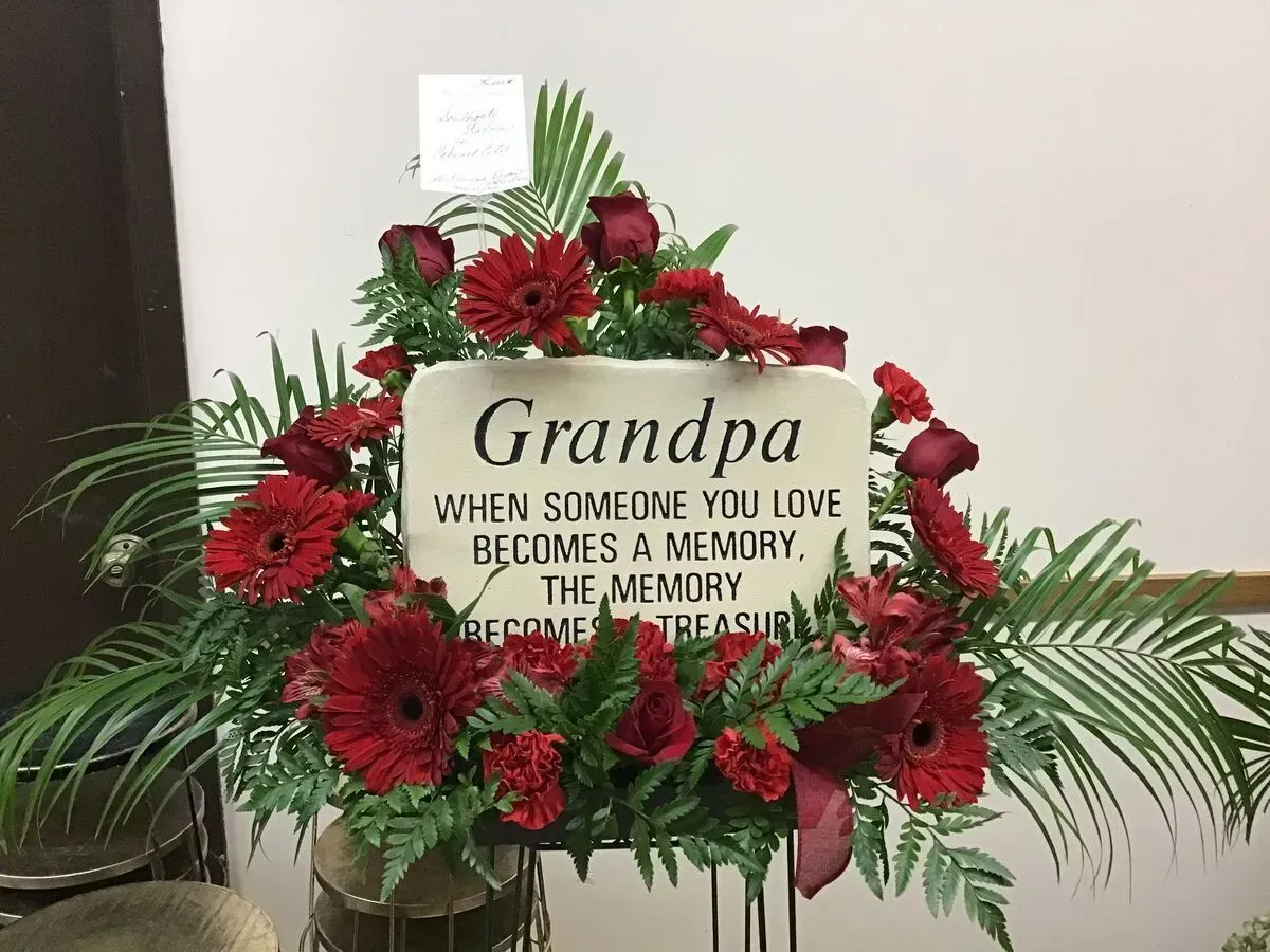 Floral arrangement for Grandpa with red flowers and a memorial plaque.