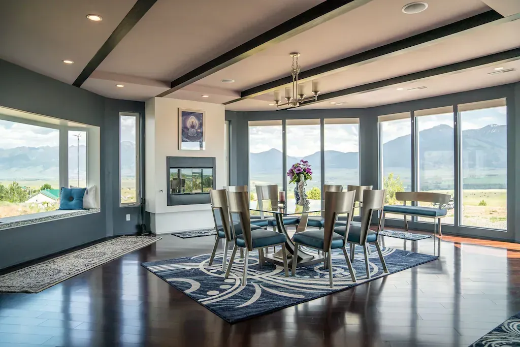 Dining room with round table, chairs, and large windows.