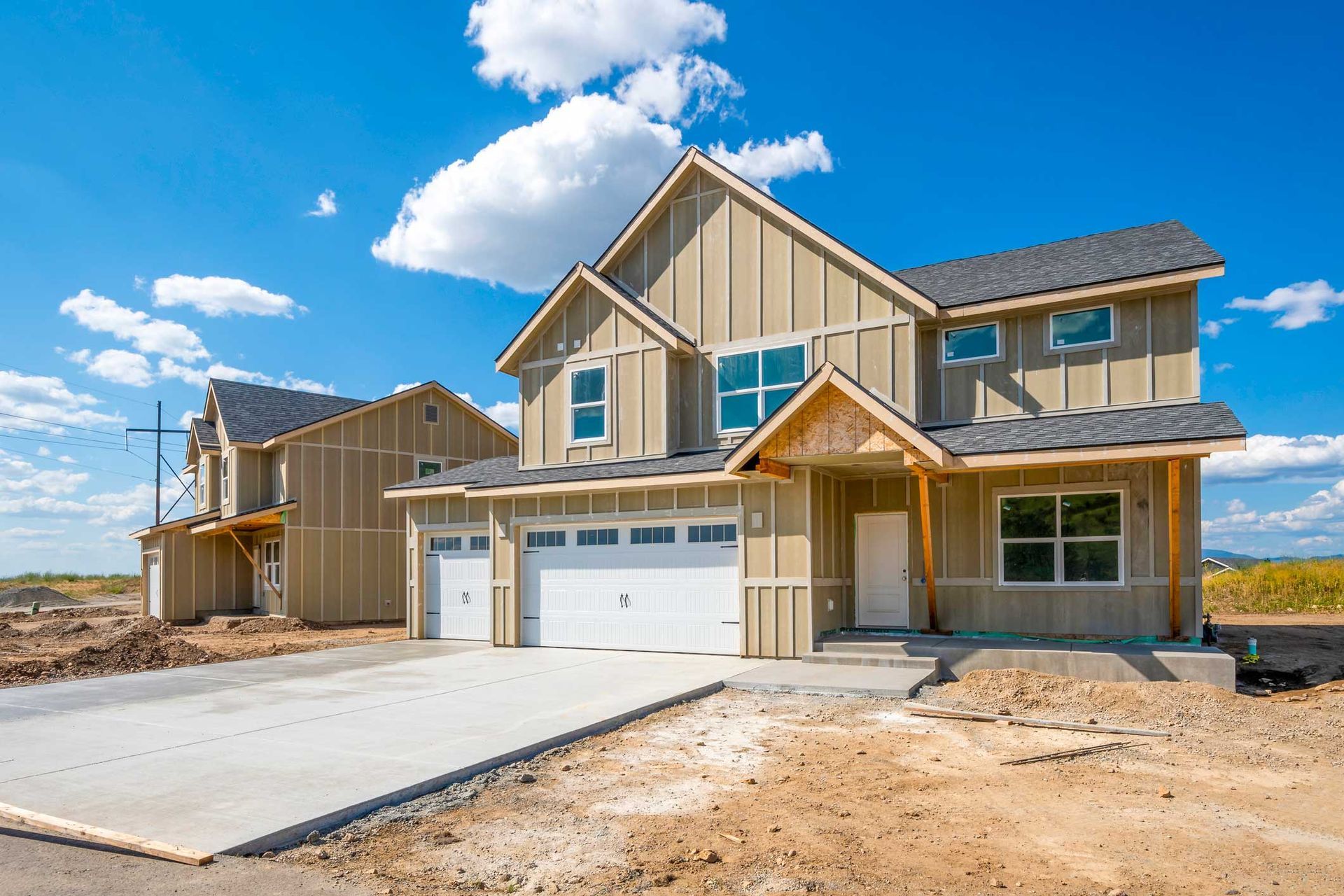 New house under construction with light brown siding and blue sky. New house under construction with light brown siding and blue sky.