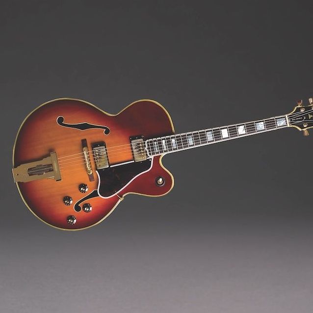 A red guitar is sitting on a gray surface