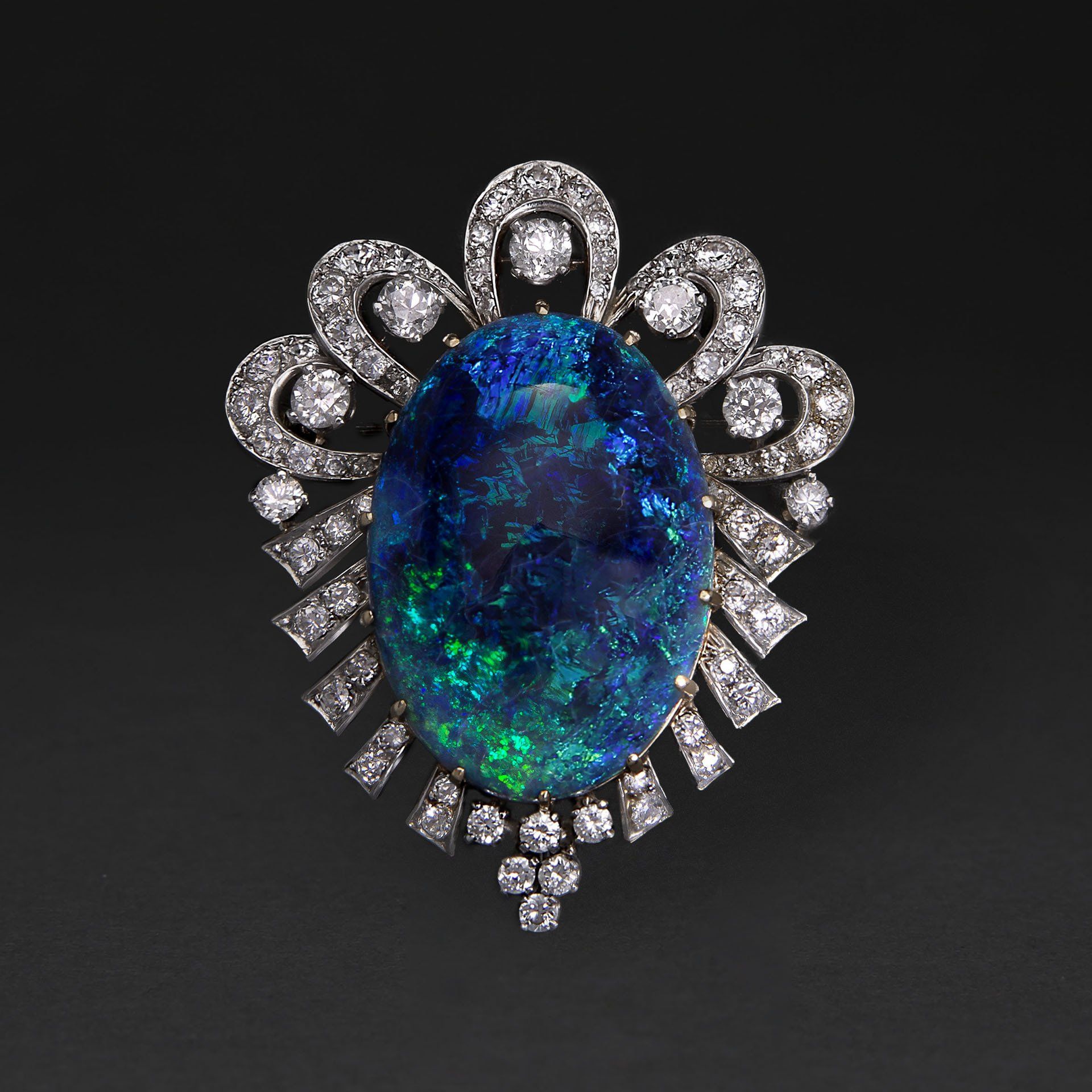 A brooch with an opal and diamonds on a black background