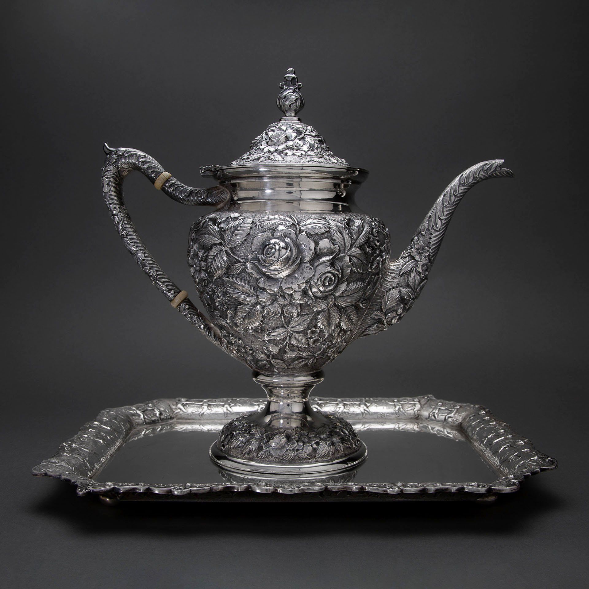 A silver teapot sitting on top of a silver tray