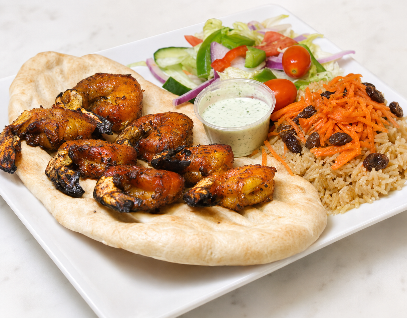 Grilled chicken with pita, rice, salad, and dipping sauce on a white plate