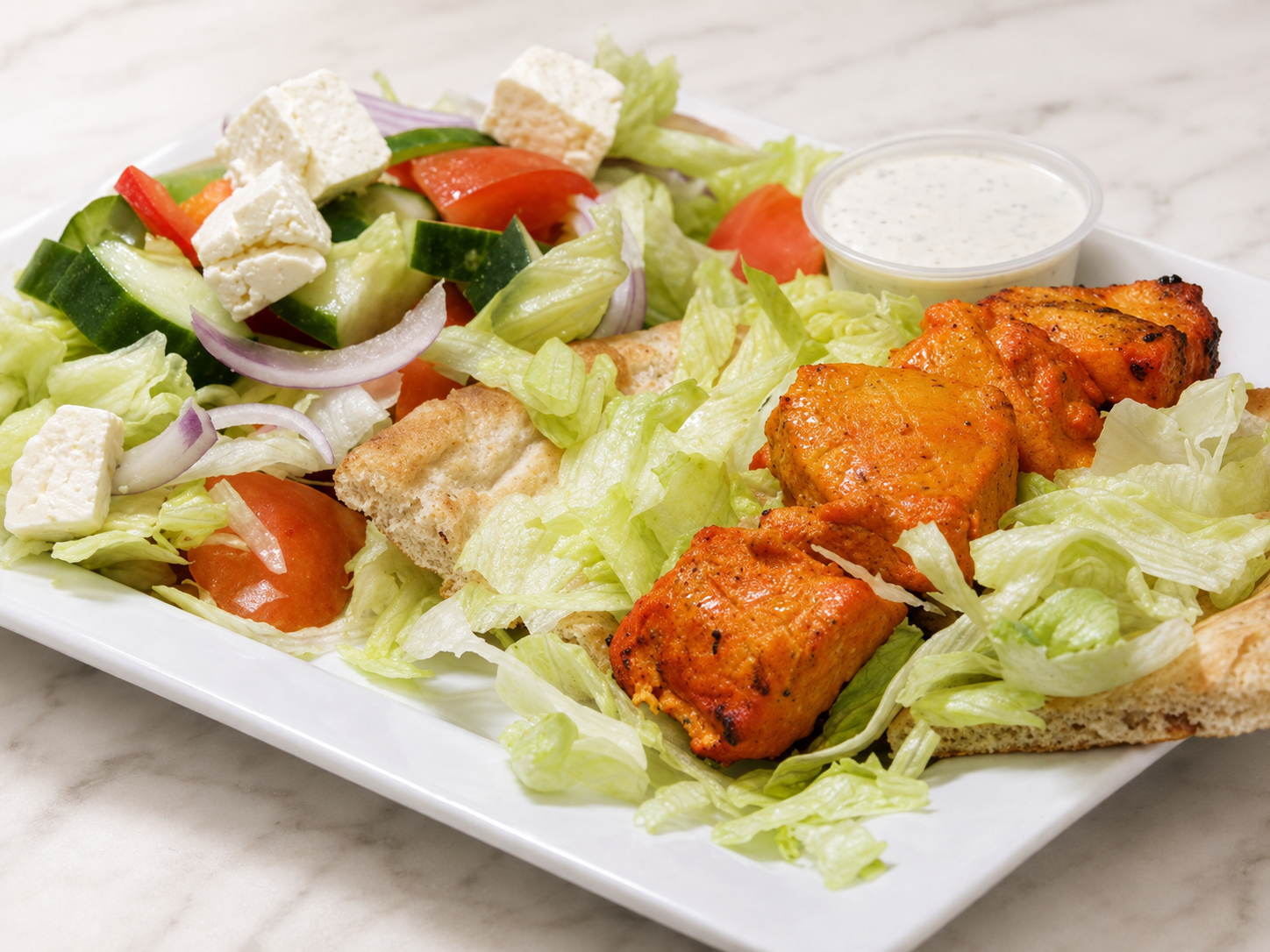 Grilled chicken and Caesar salad on a white plate with lettuce, tomatoes, croutons, and dressing cup