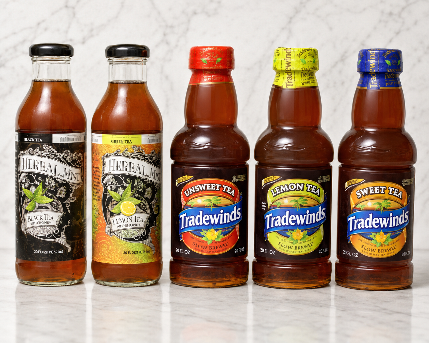 Five bottles of hot sauce in assorted colors lined up on a white countertop.