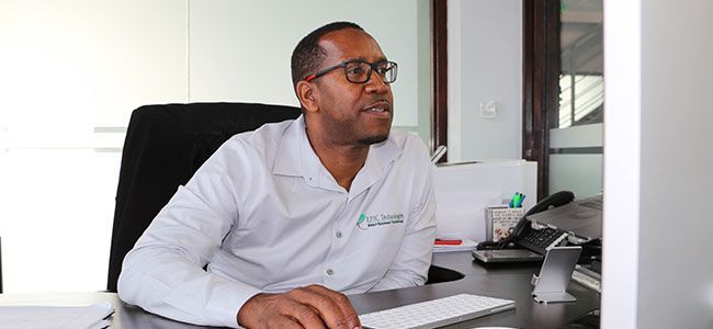 Person seated at a desk in an office, looking to the right while using a computer