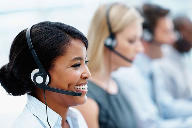 Call center staff wearing headsets, with a smiling agent in focus