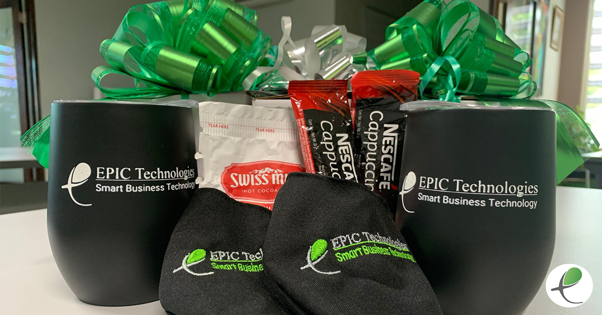 Gift basket with two black tumblers, coffee packets, socks, and green bow.