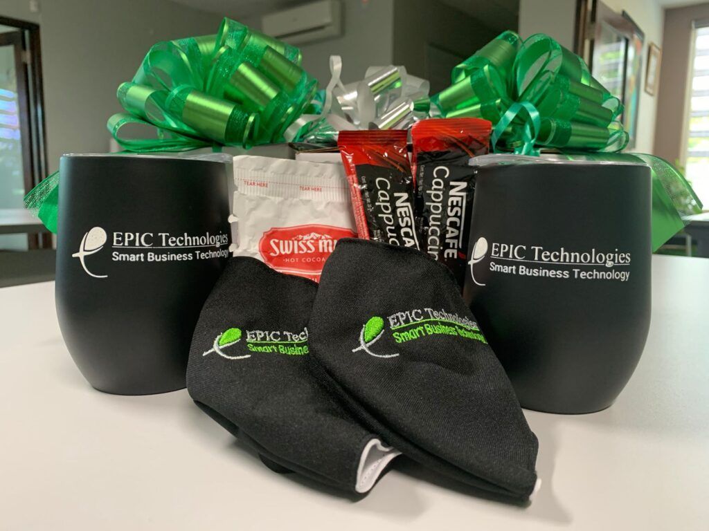 Gift basket with black tumblers, coffee, sanitizing wipes, and elbow supports with bows.