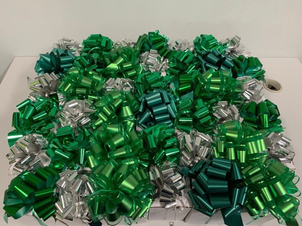 Green and silver gift bows on a white surface.