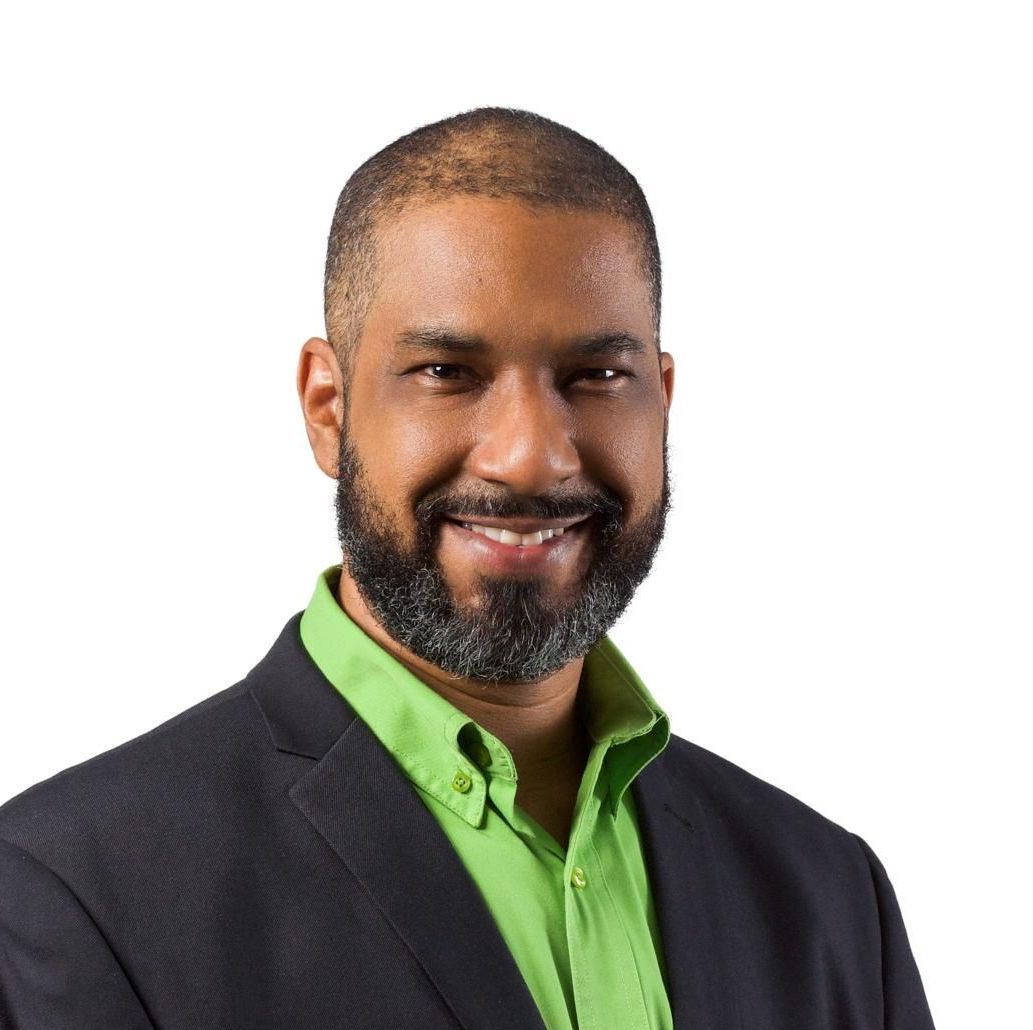 Smiling man in a dark suit and bright green shirt on a white background