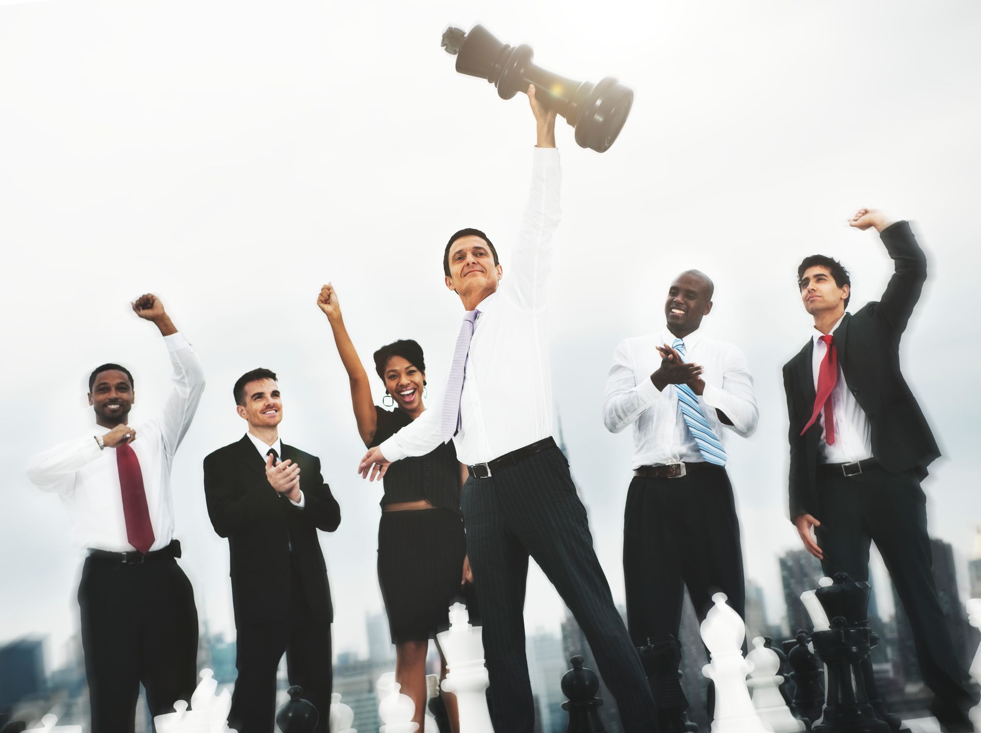 Business team celebrating a chess victory, man holding a chess piece high.