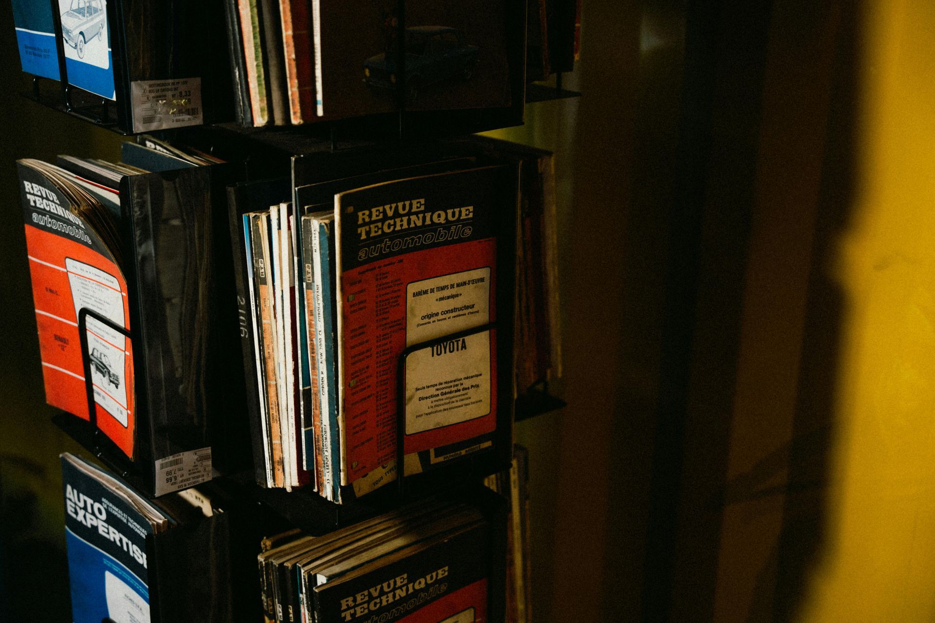 Books and magazines on a shelf beside a yellow wall