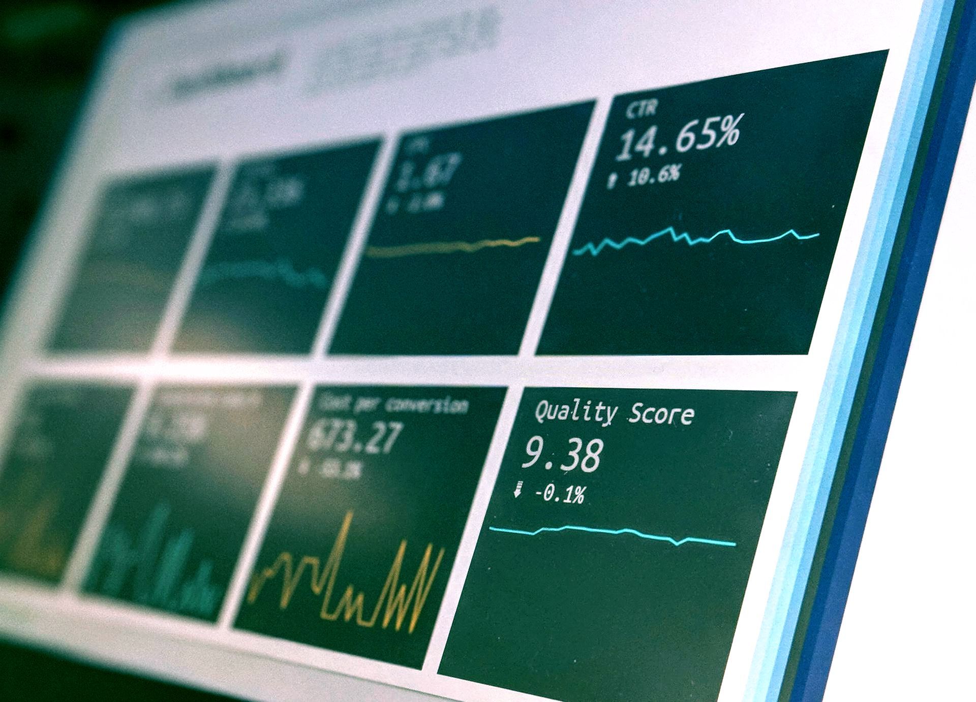 Analytics dashboard with green metric tiles and line charts on a tilted screen