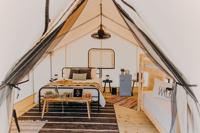 A tent with a bed and a rug inside of it.