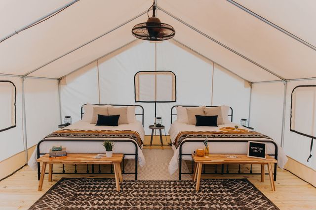A tent with two beds and a rug in it